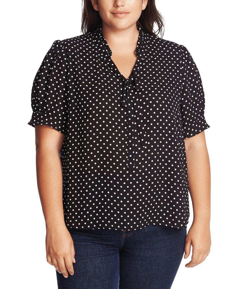 Front of a model wearing a size 1X Molly Polka-Dot Tie-Neck Top in 060-RICH BLACK by CeCe. | dia_product_style_image_id:263870